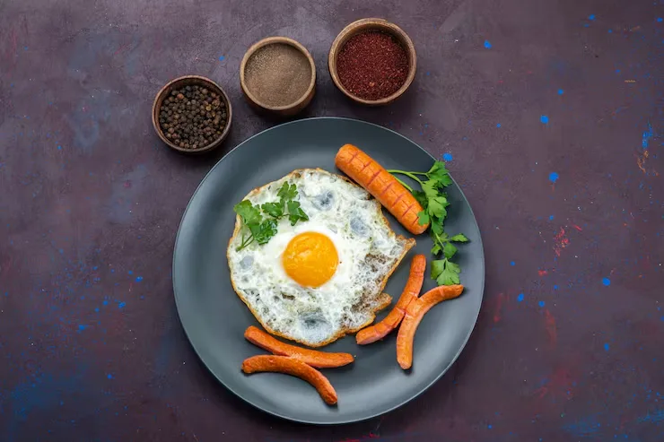 top-view-scrambled-eggs-with-sausages-seasonings-dark-surface